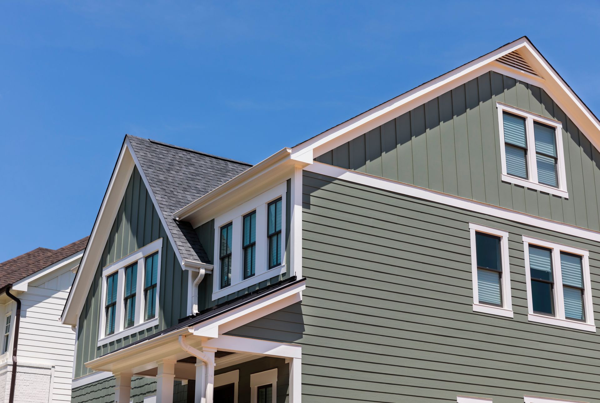 Contemporary suburban home with sage green siding and a white trim.