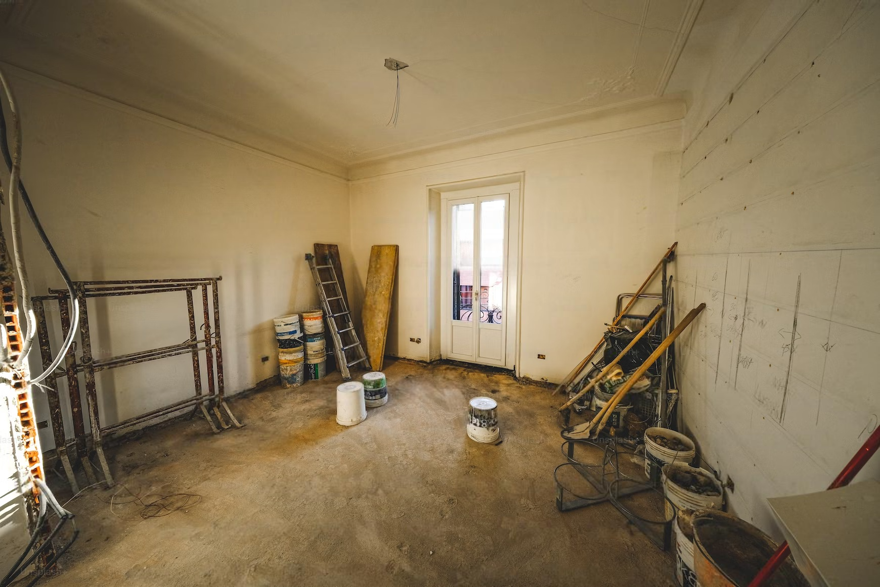 a room with a ladder and buckets of paint in it .