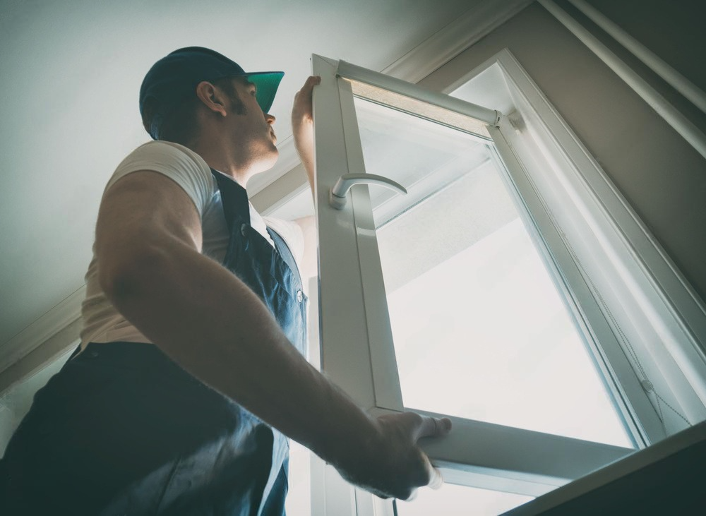 a man in overalls is installing a window