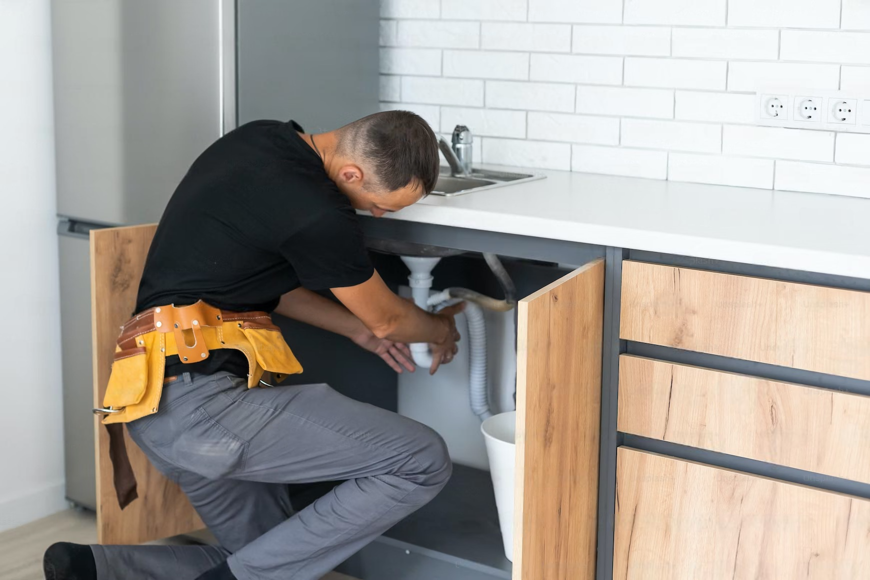 a man is fixing a sink in a kitchen