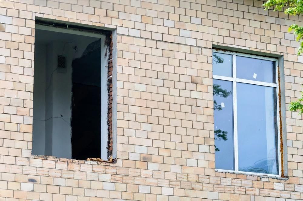 A brick building with two windows and a door missing