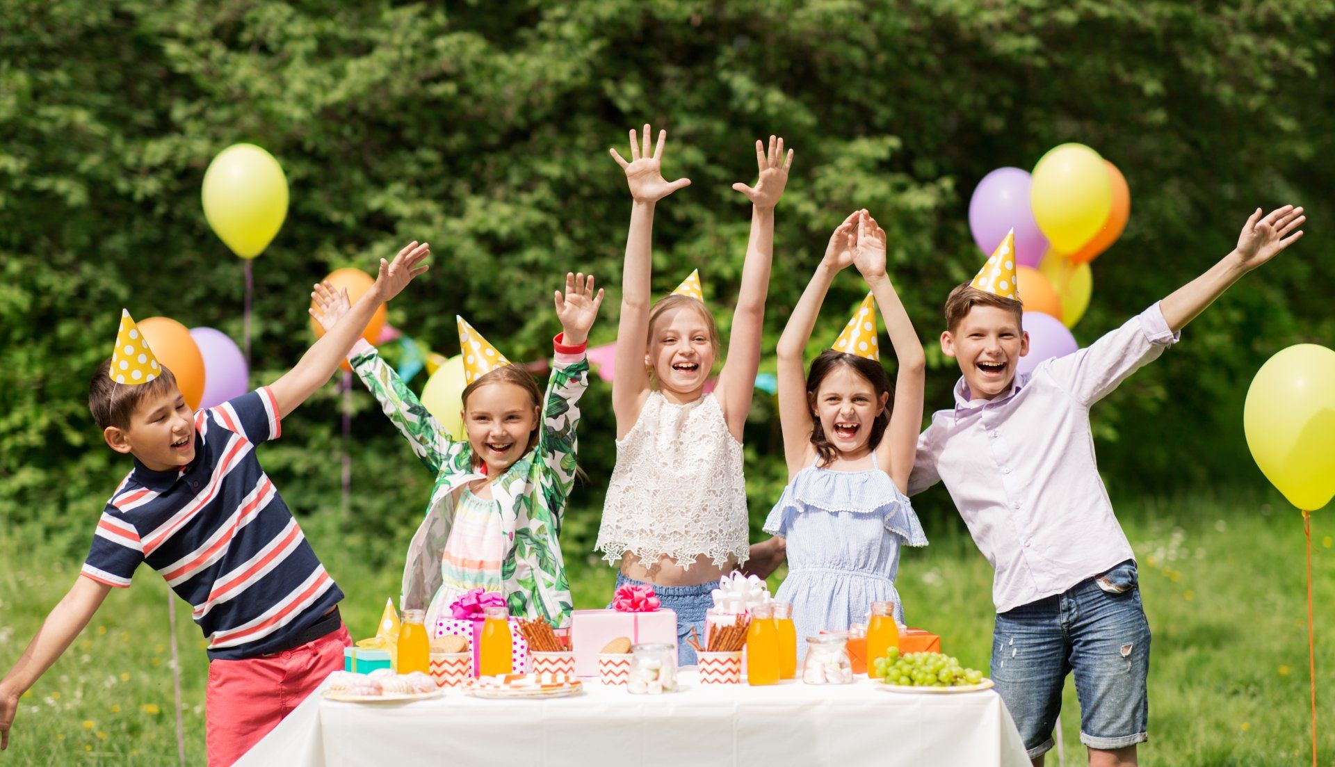 holidays, childhood and celebration concept - happy kids hugging on birthday party at summer garden
