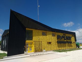 Abrazadera metálica y perfiles de aluminio sobre un banco de trabajo de madera con una regla y tornillos pequeños.