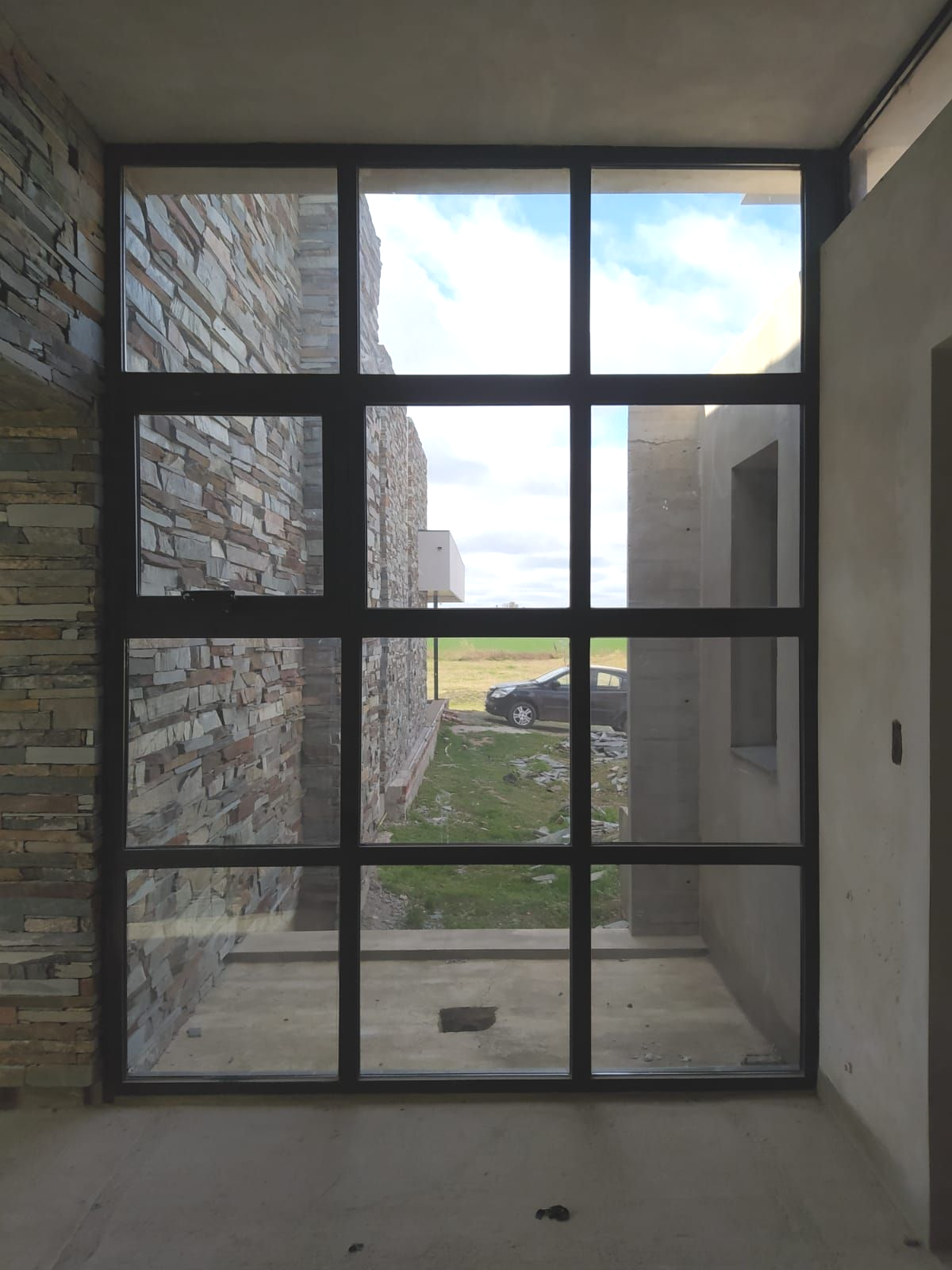 Edificio moderno con fachada de cristal, una piscina poco profunda y algunas personas de pie cerca de la entrada.