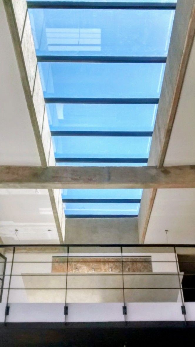 Vista interior del atrio de un edificio con una gran claraboya azul y una barandilla metálica en la parte inferior.