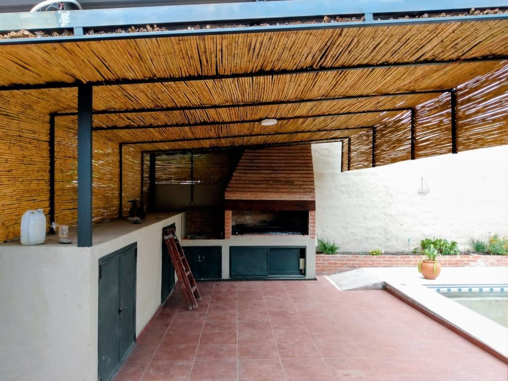 Patio al aire libre con techo de paja, suelo de baldosas rojas y bancos y mostradores empotrados.