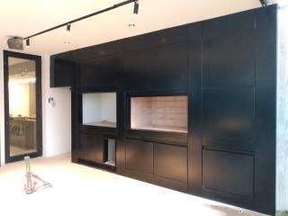 Habitación moderna con un gran mueble empotrado negro y estantes de exposición sobre paredes blancas.