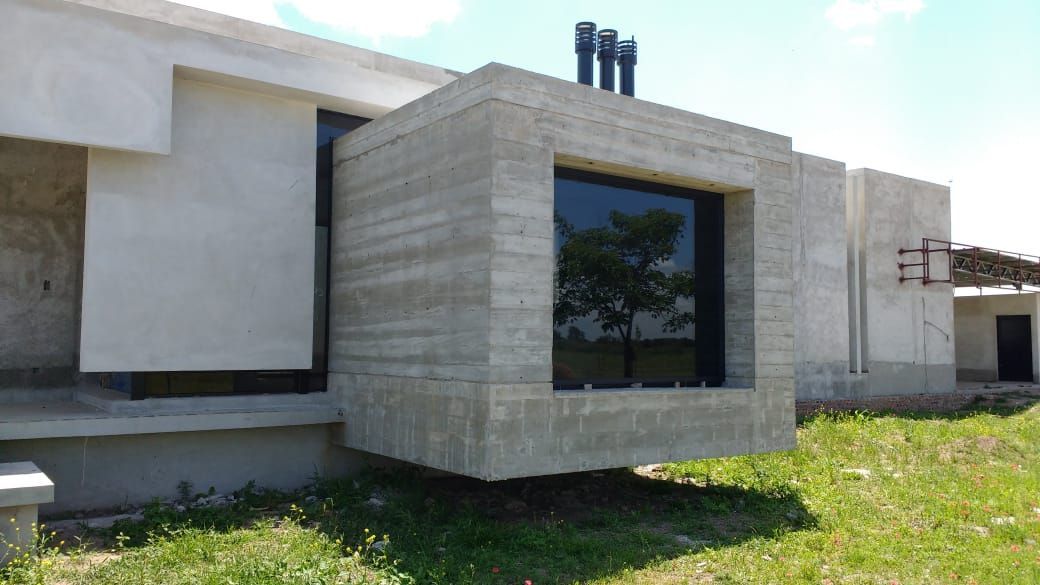 Exterior de una casa moderna de color blanco con un ventanal revestido de piedra y un jardín con césped.