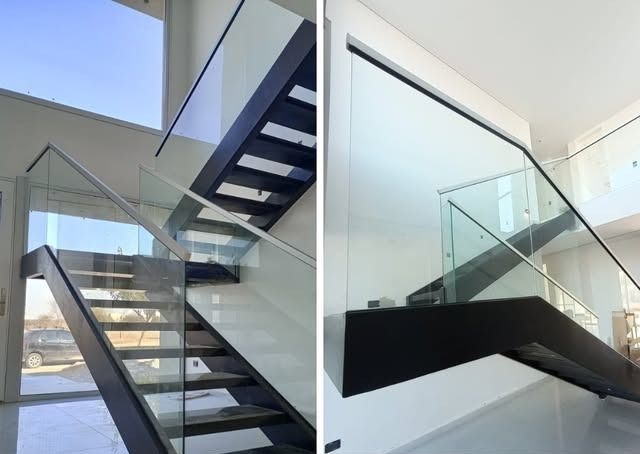 Escalera moderna con barandillas de cristal y detalles en negro en un interior blanco luminoso.