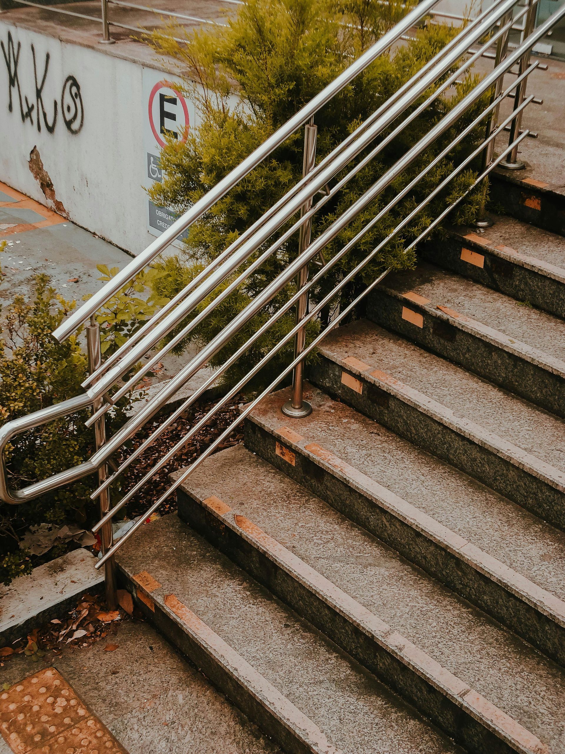 Escaleras exteriores oxidadas con pasamanos de metal junto a una pared cubierta de grafitis.