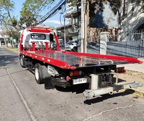 Una grúa roja está estacionada al costado de la carretera.