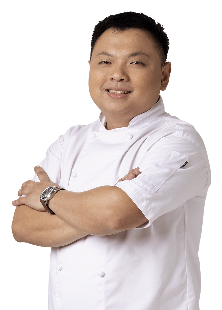 Chef with arms crossed, smiling, wearing white chef's coat, watch visible.