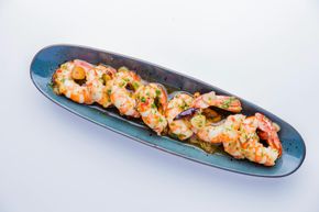 Cooked shrimp in garlic butter, served on a blue oval plate.
