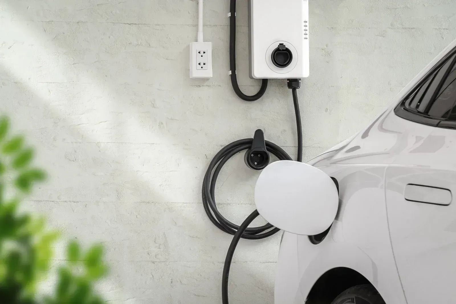 Electric car charging at a wall-mounted charger in a garage