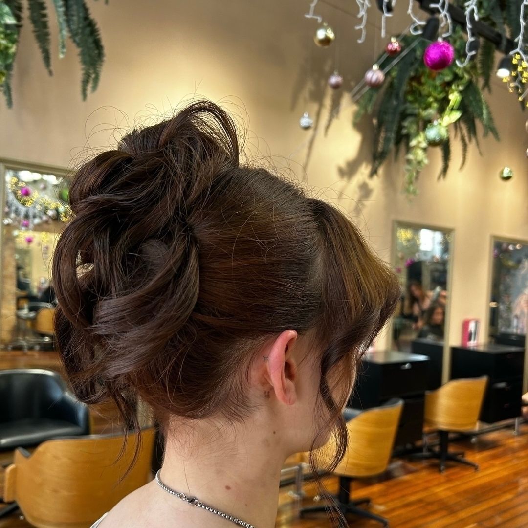 Woman with brown hair in an updo hairstyle in a salon setting.