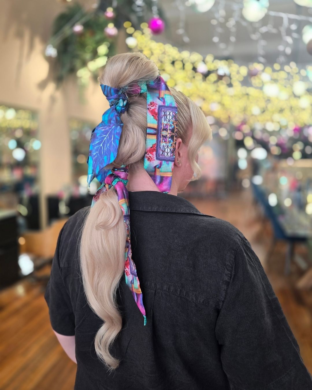 Woman with blonde hair styled with colourful silk scarves in a salon setting.
