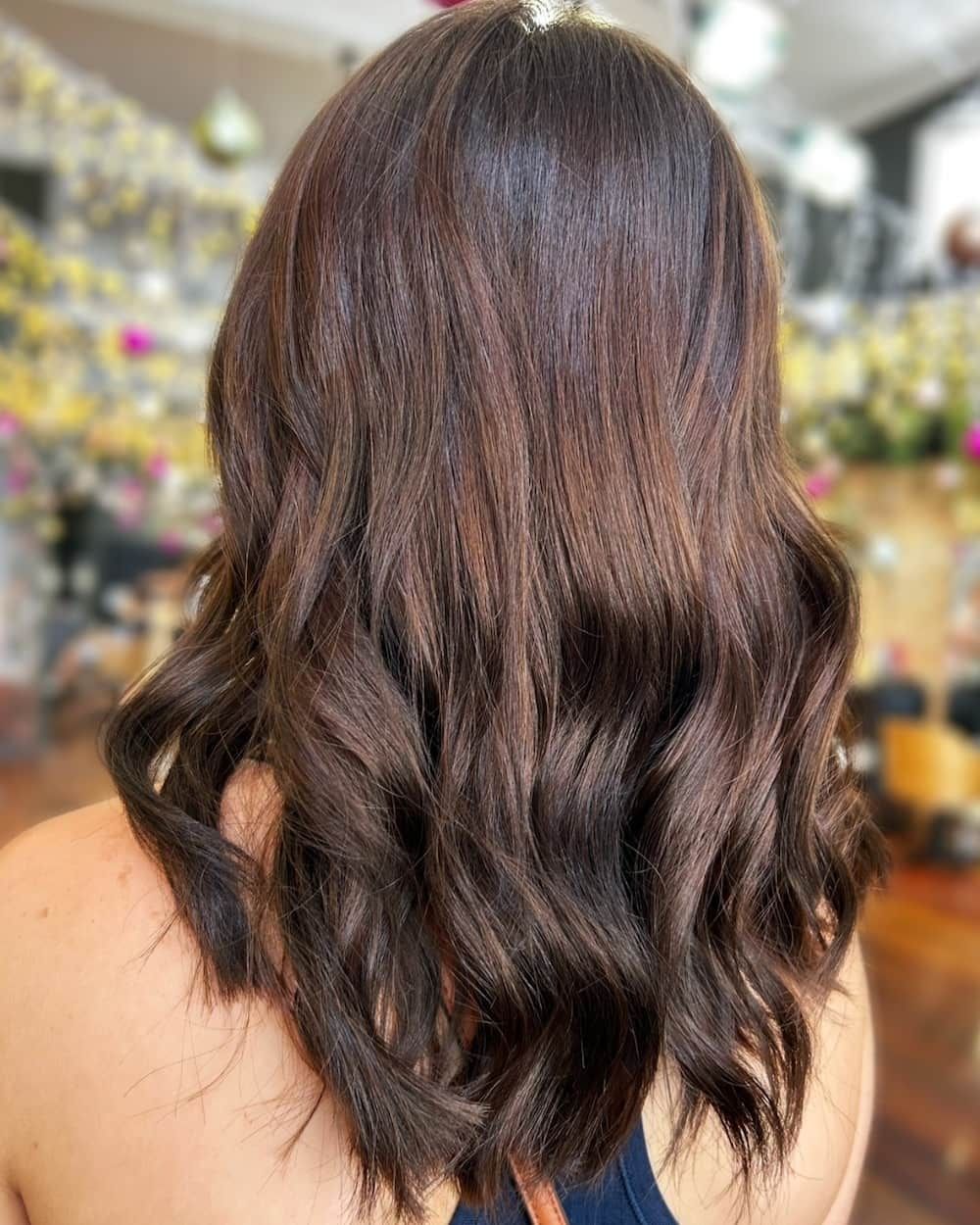 Woman with wavy dark brown hair, styled in a salon.