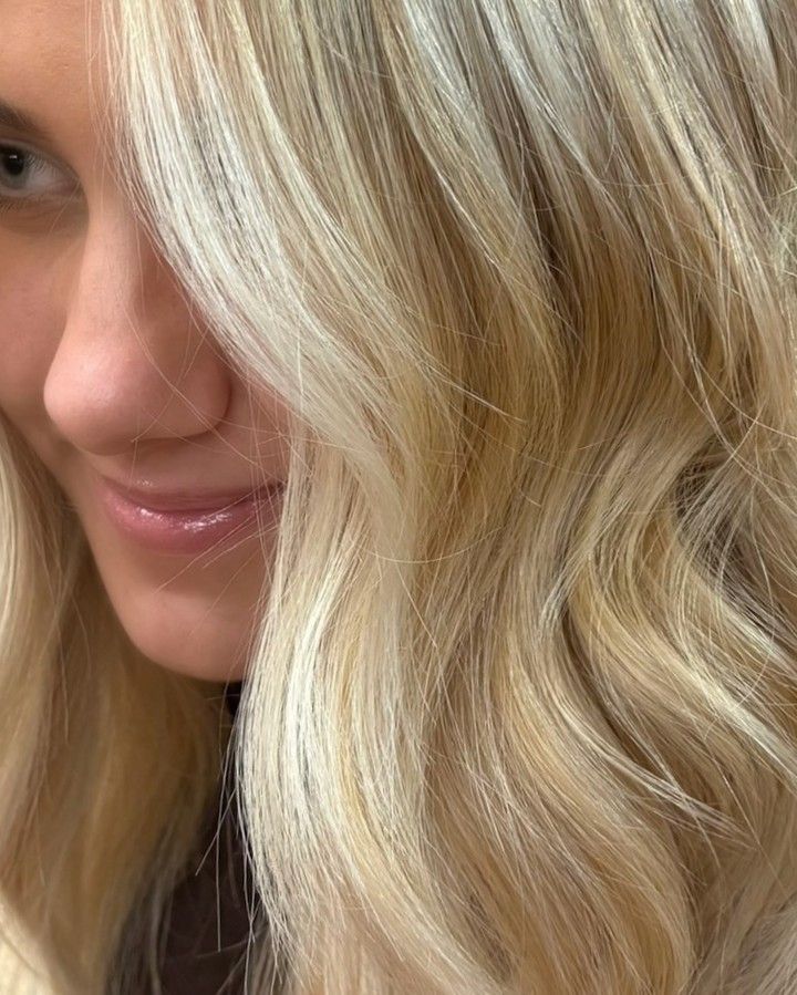 Blonde woman with wavy hair, close-up showing smile and facial features.