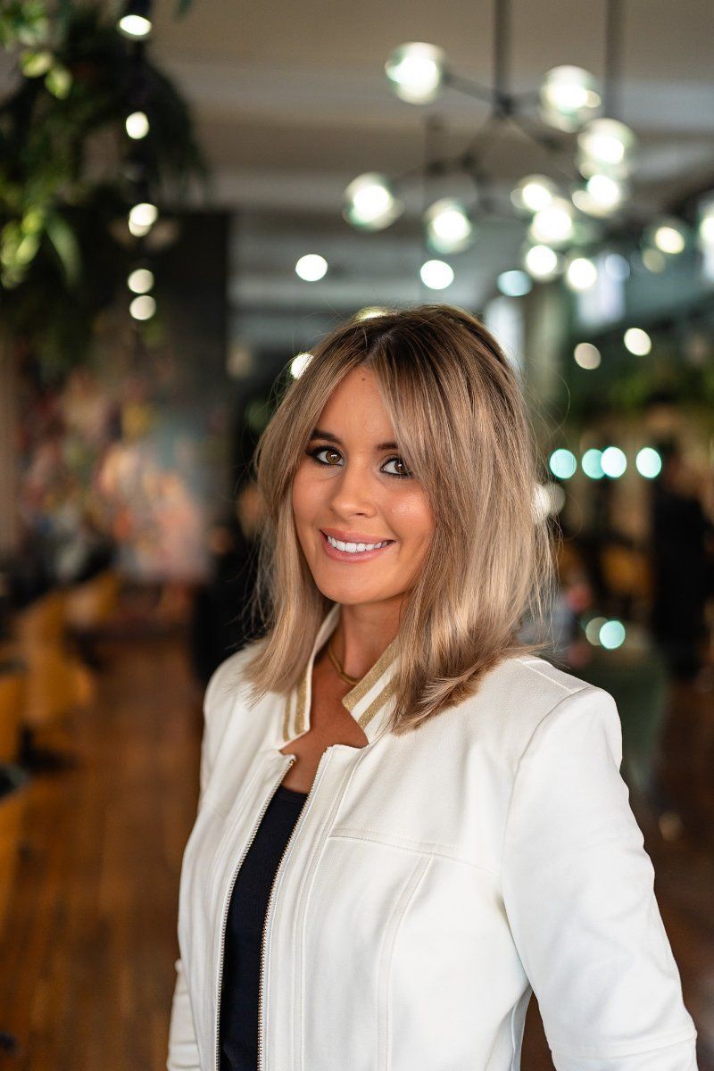 A Woman is Wearing a White Jacket and Smiling for the Camera — Air Hair Studio in Toowoomba City, QLD
