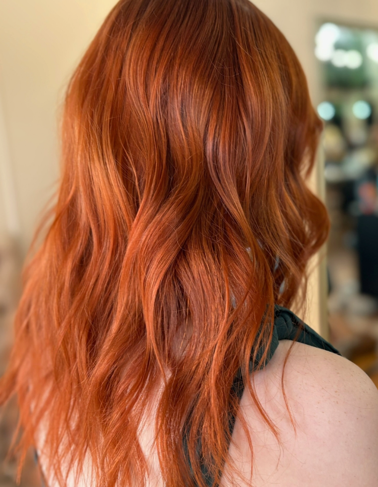 A woman with long red hair is wearing a black tank top.