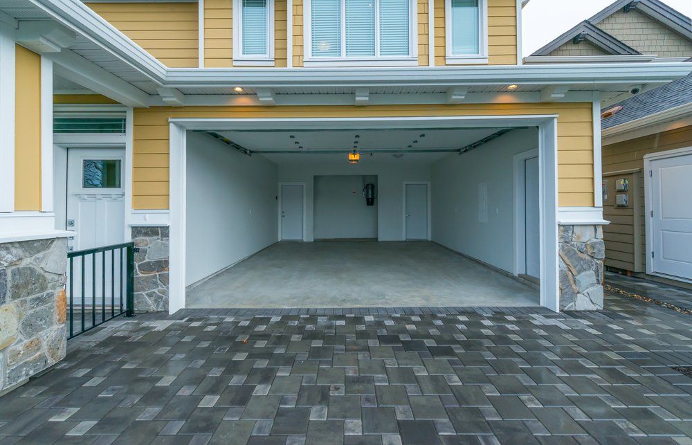 An empty garage with a brick driveway in front of a house.