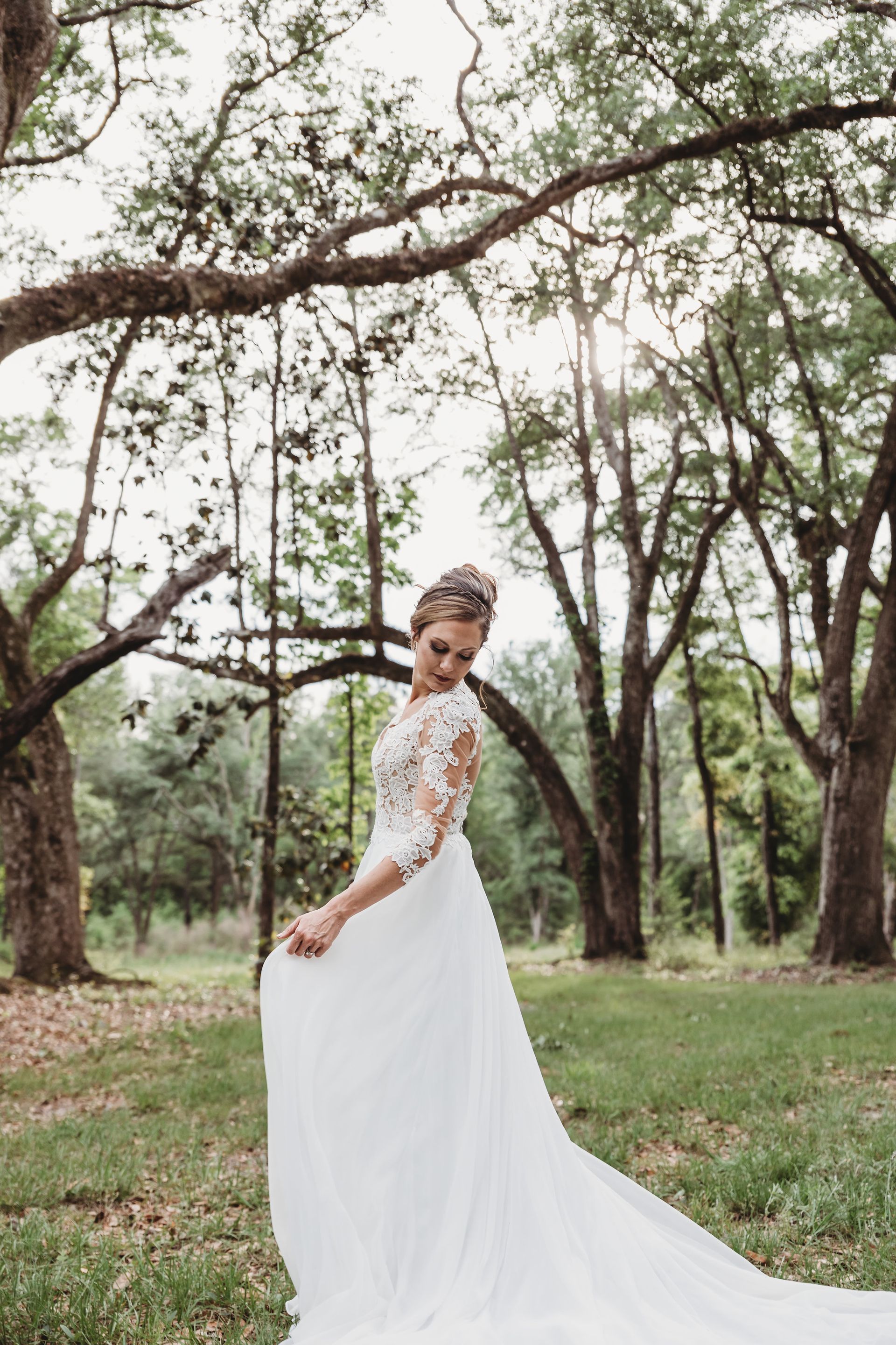 bride standing surrounded by green trees