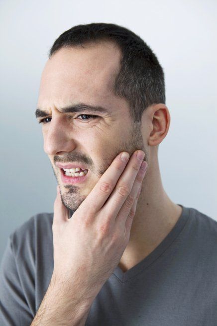man with TMJ problems holding his jaw