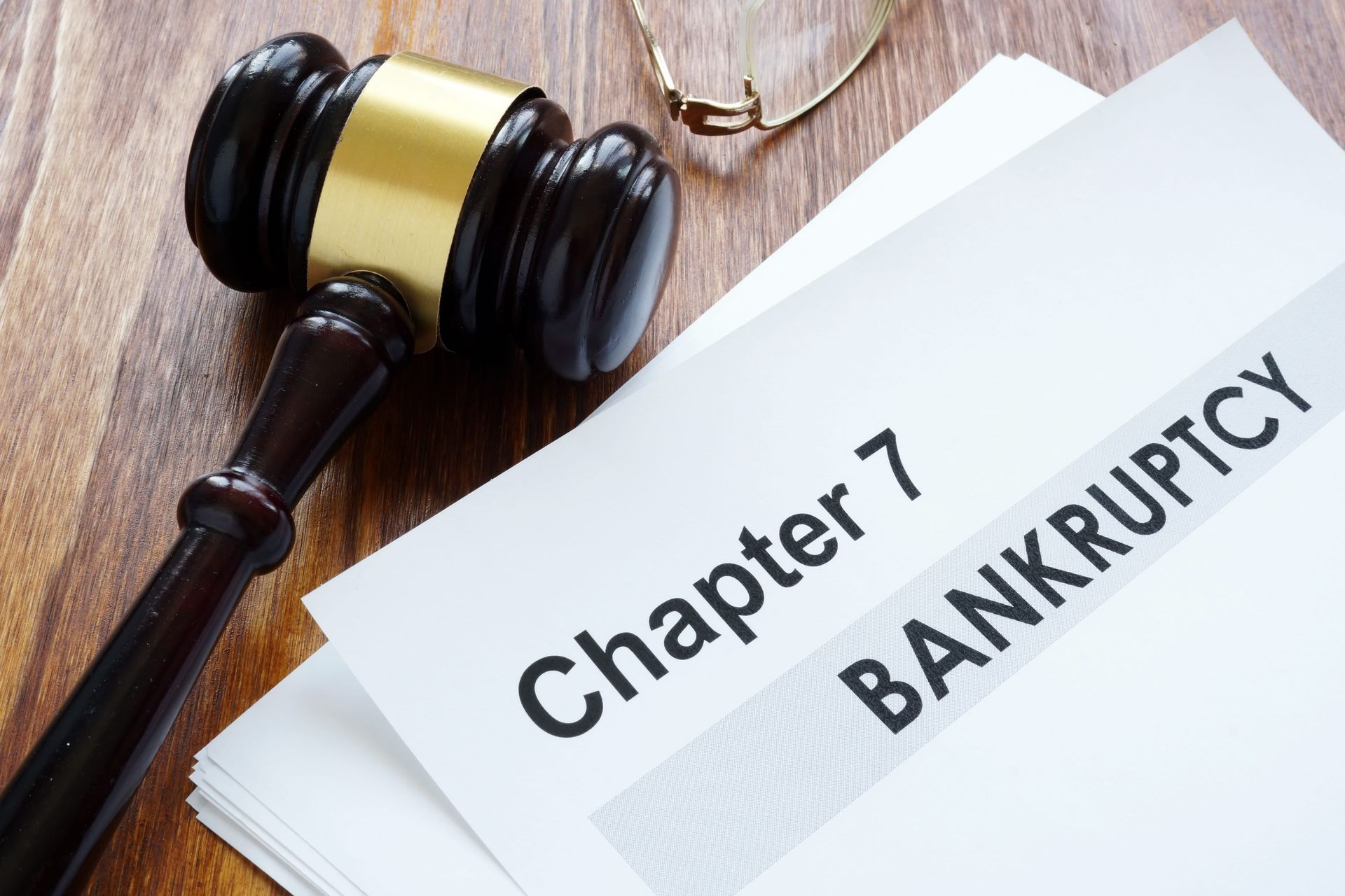 Gavel beside a paper labeled “Chapter 7 Bankruptcy” on a wooden desk
