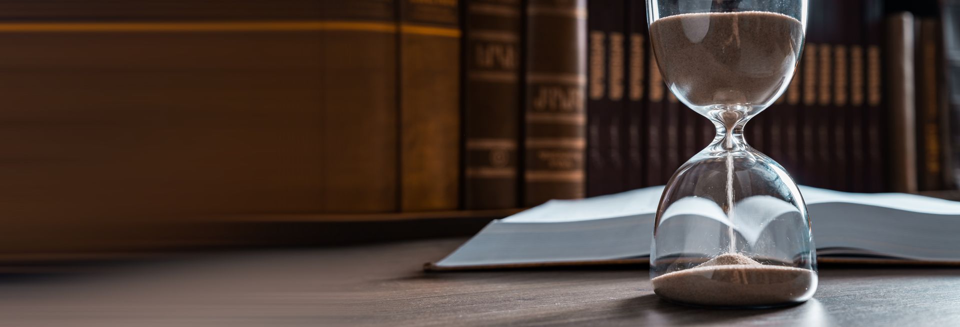 An hourglass sits on a table with an open book symbolizing quiet title actions in San Diego.