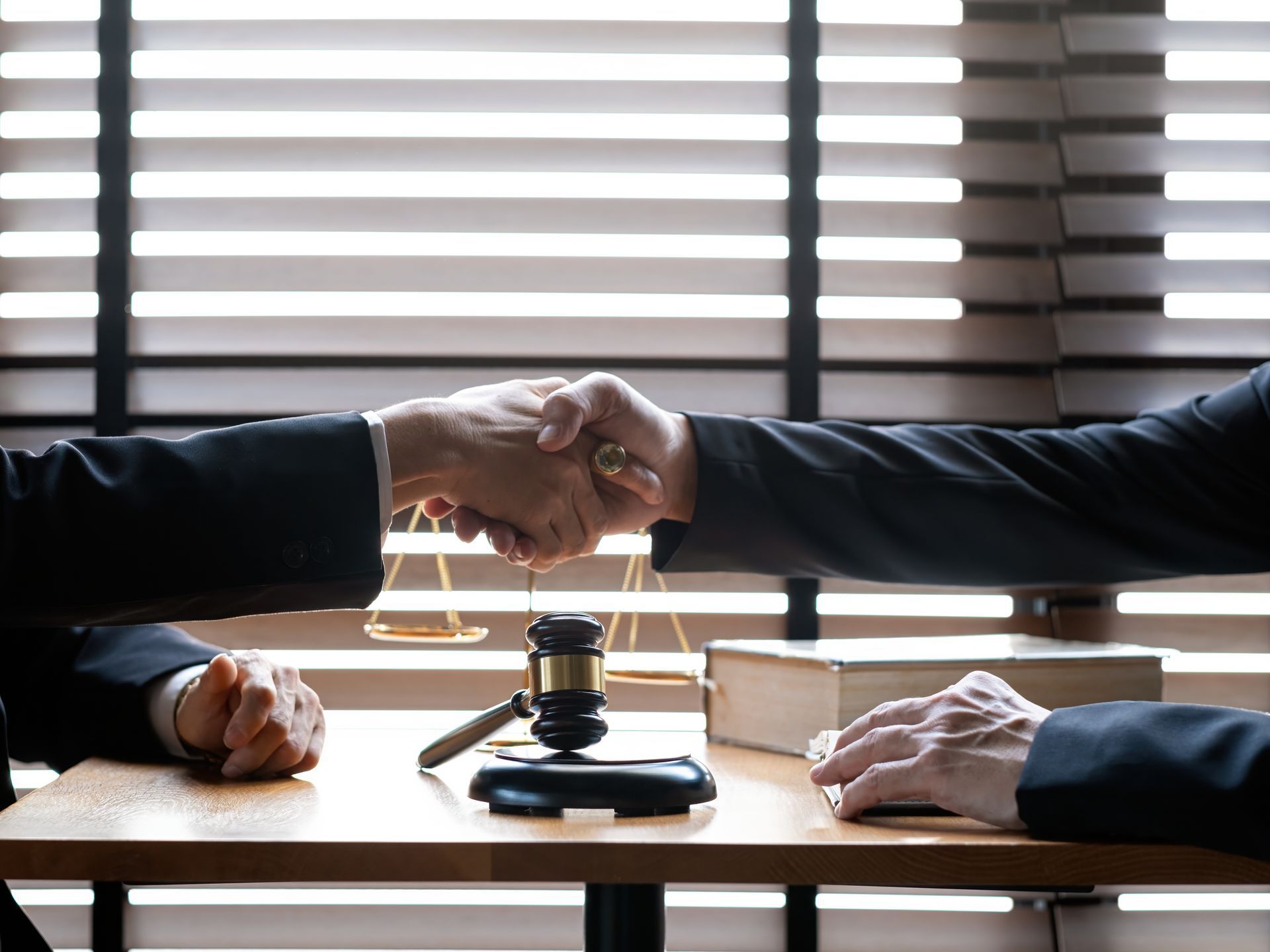 Two people in suits shake hands over a table representing transaction law in San Diego, California.