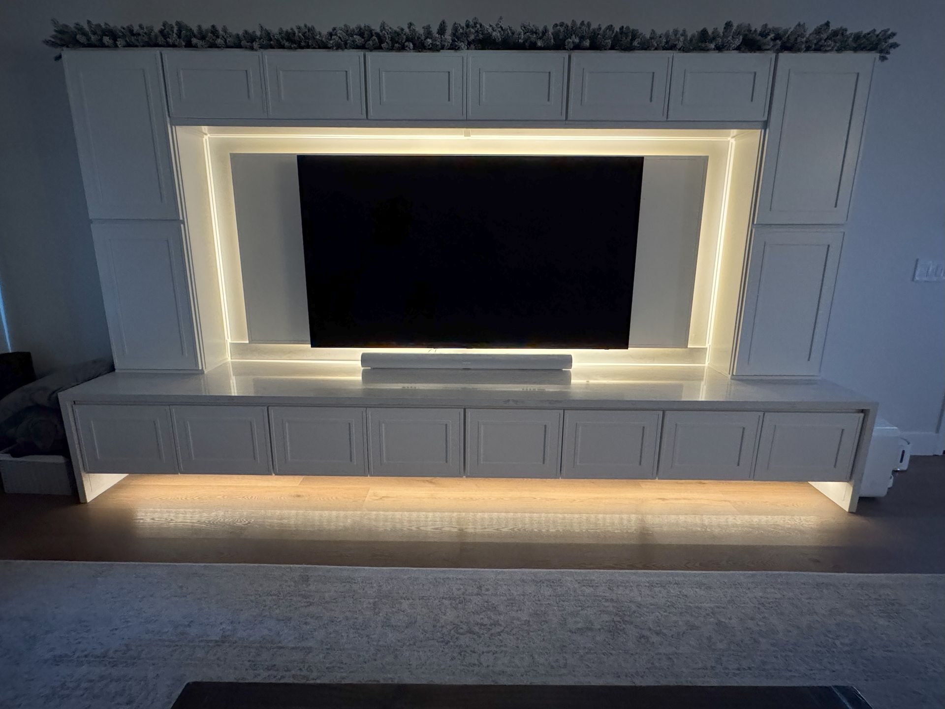 White entertainment center with a TV and LED strip lighting.