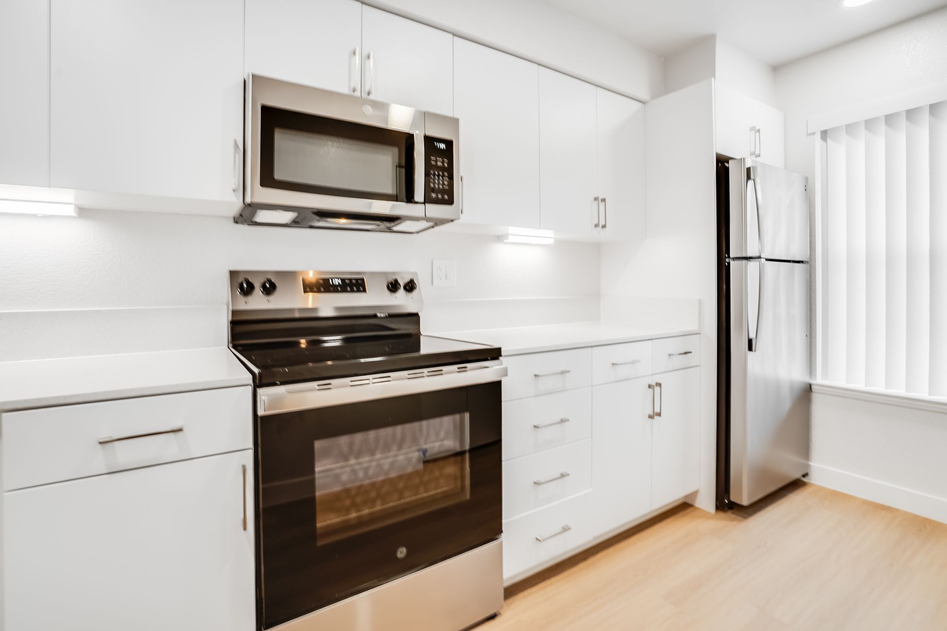 Modern white kitchen with stainless steel appliances.