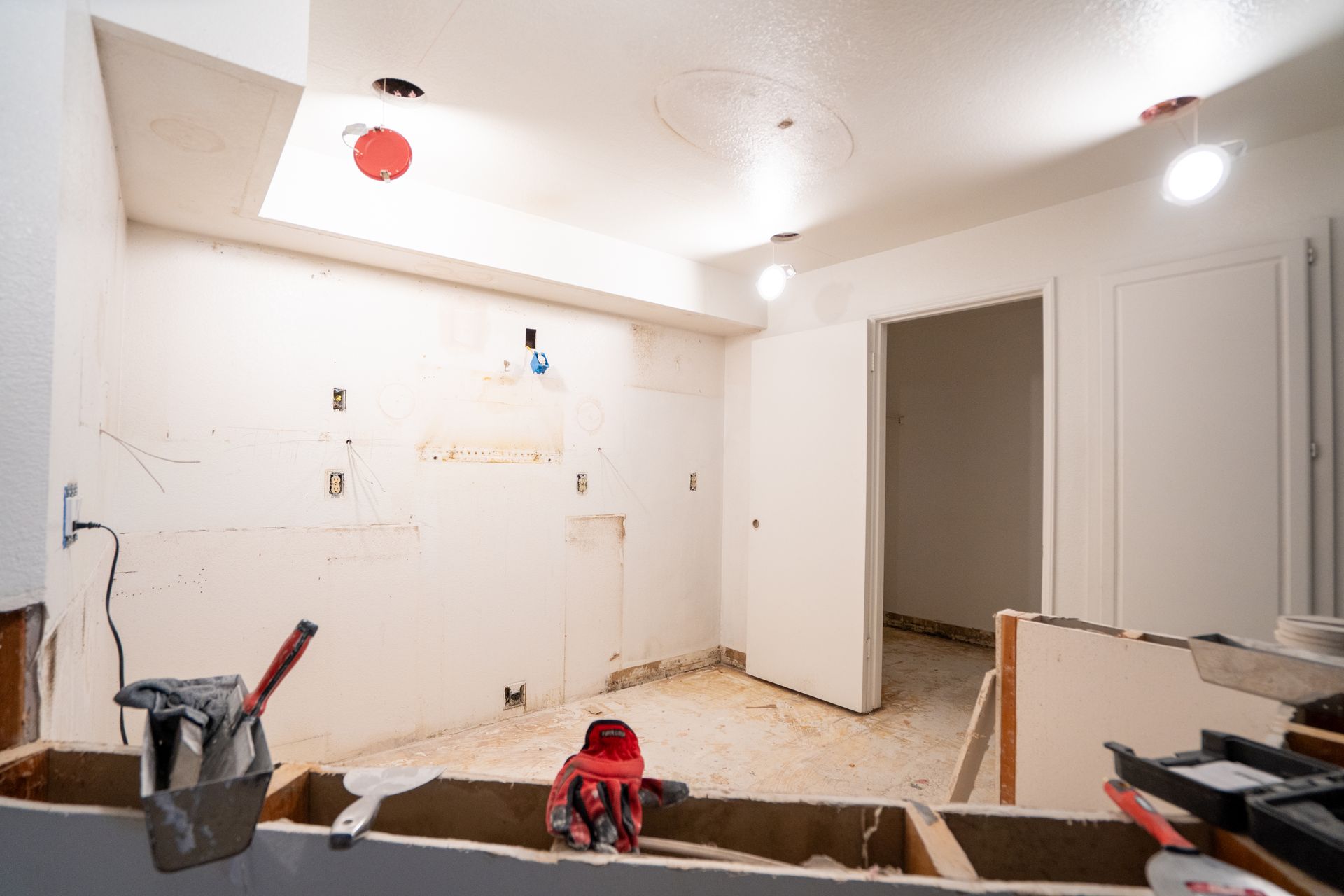 Kitchen remodel in progress, walls stripped bare, door open to another room.