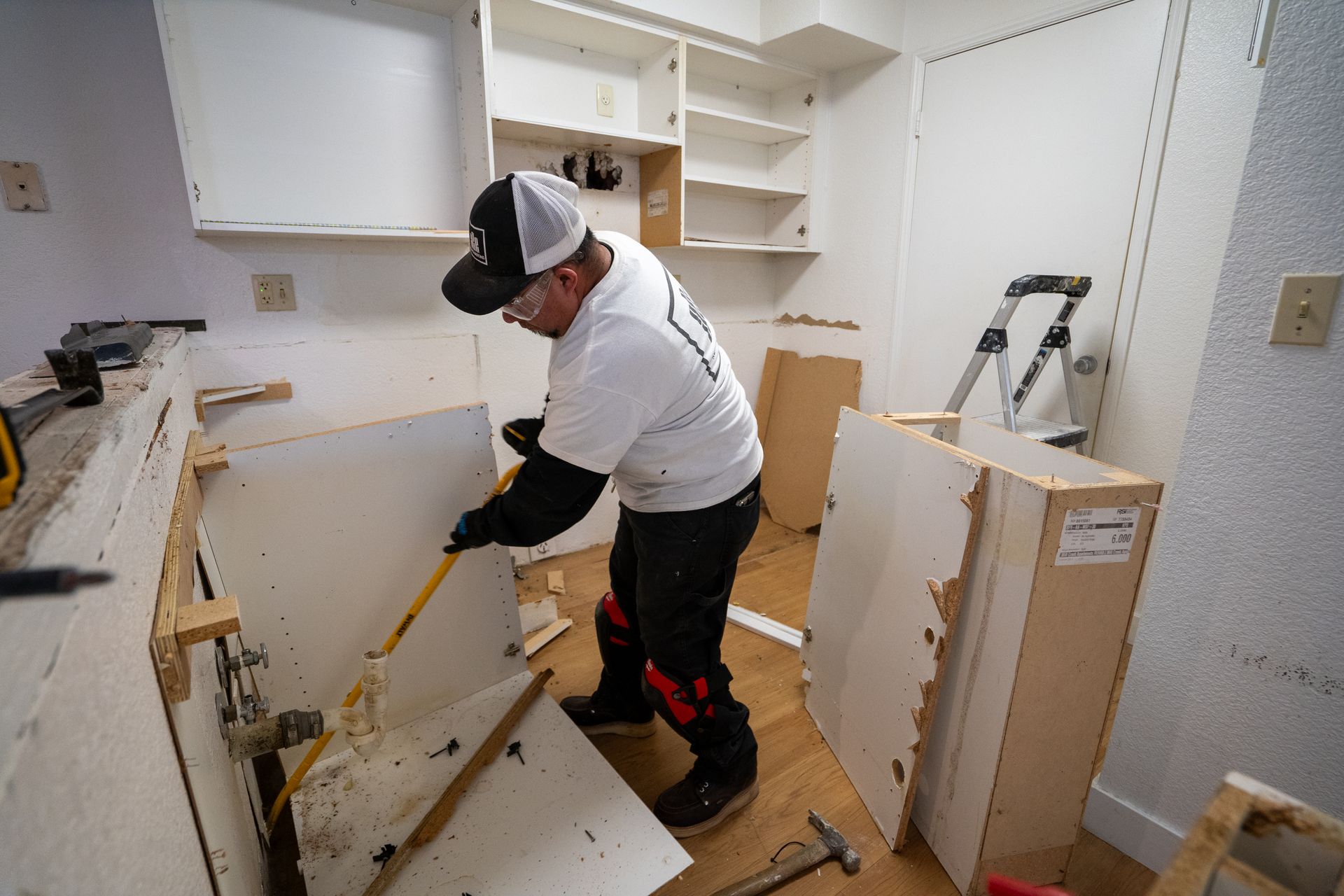 Person removing a kitchen cabinet with a crowbar.
