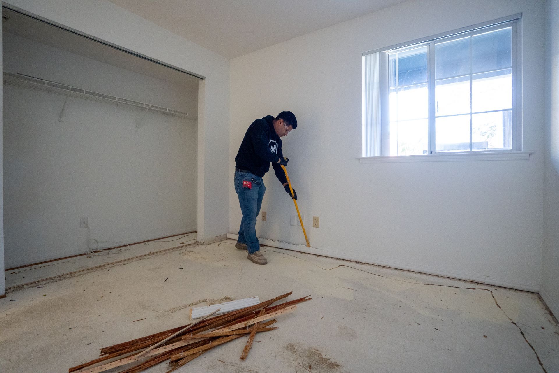 Person removing baseboard in a room.