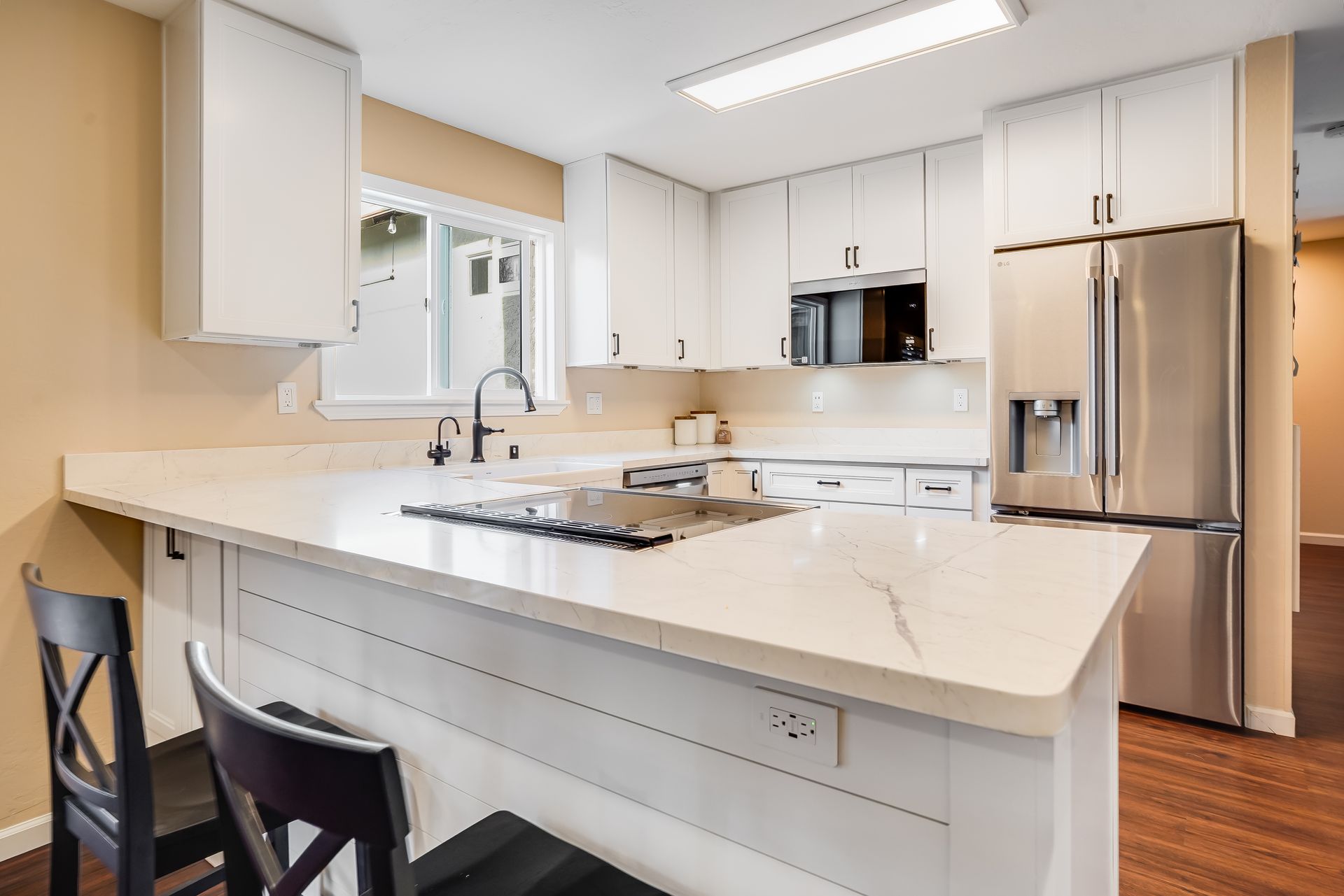 Modern kitchen with white cabinets, stainless steel appliances, and white countertops.