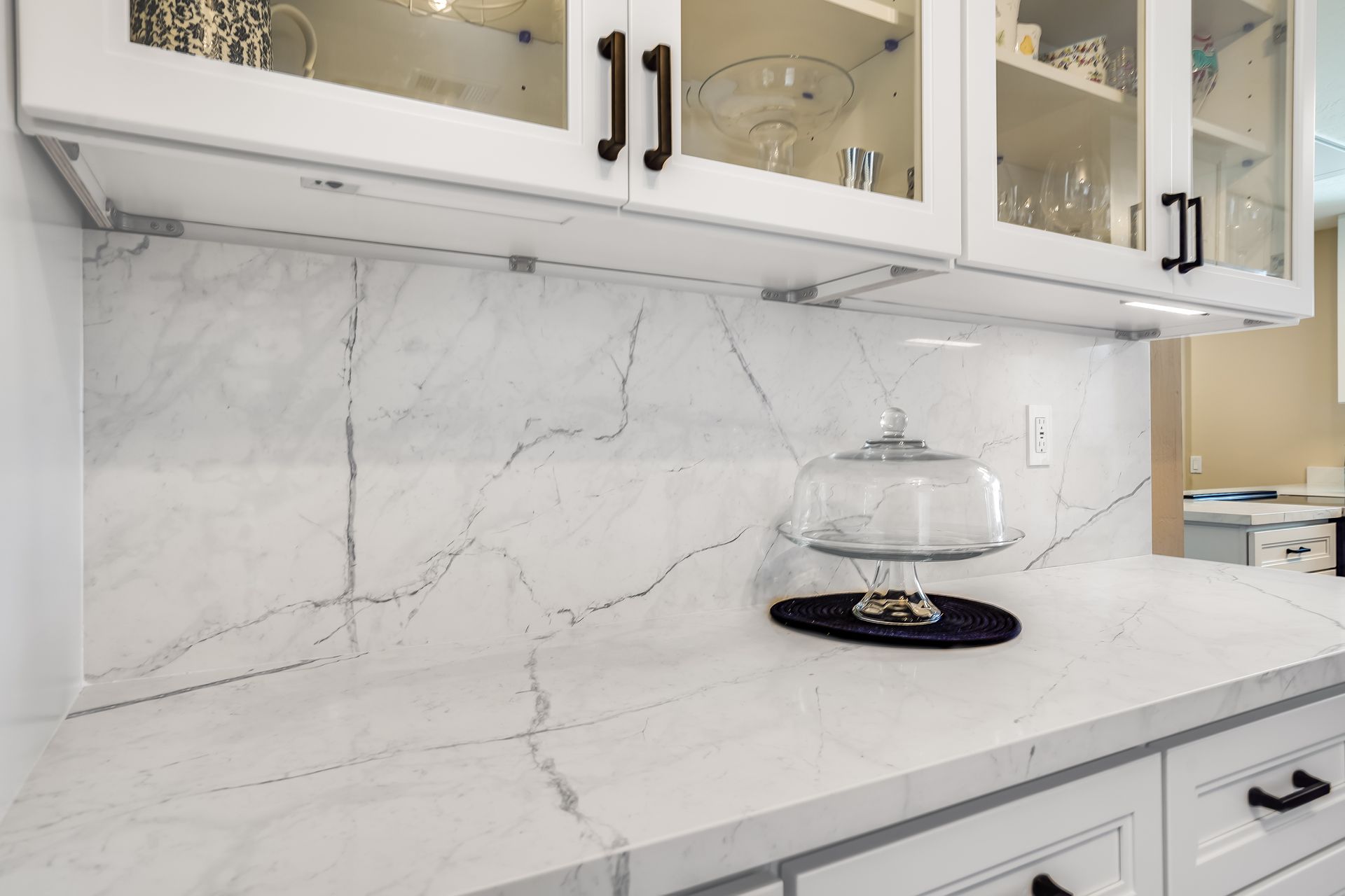 White kitchen countertop with marble-like backsplash and upper cabinets.