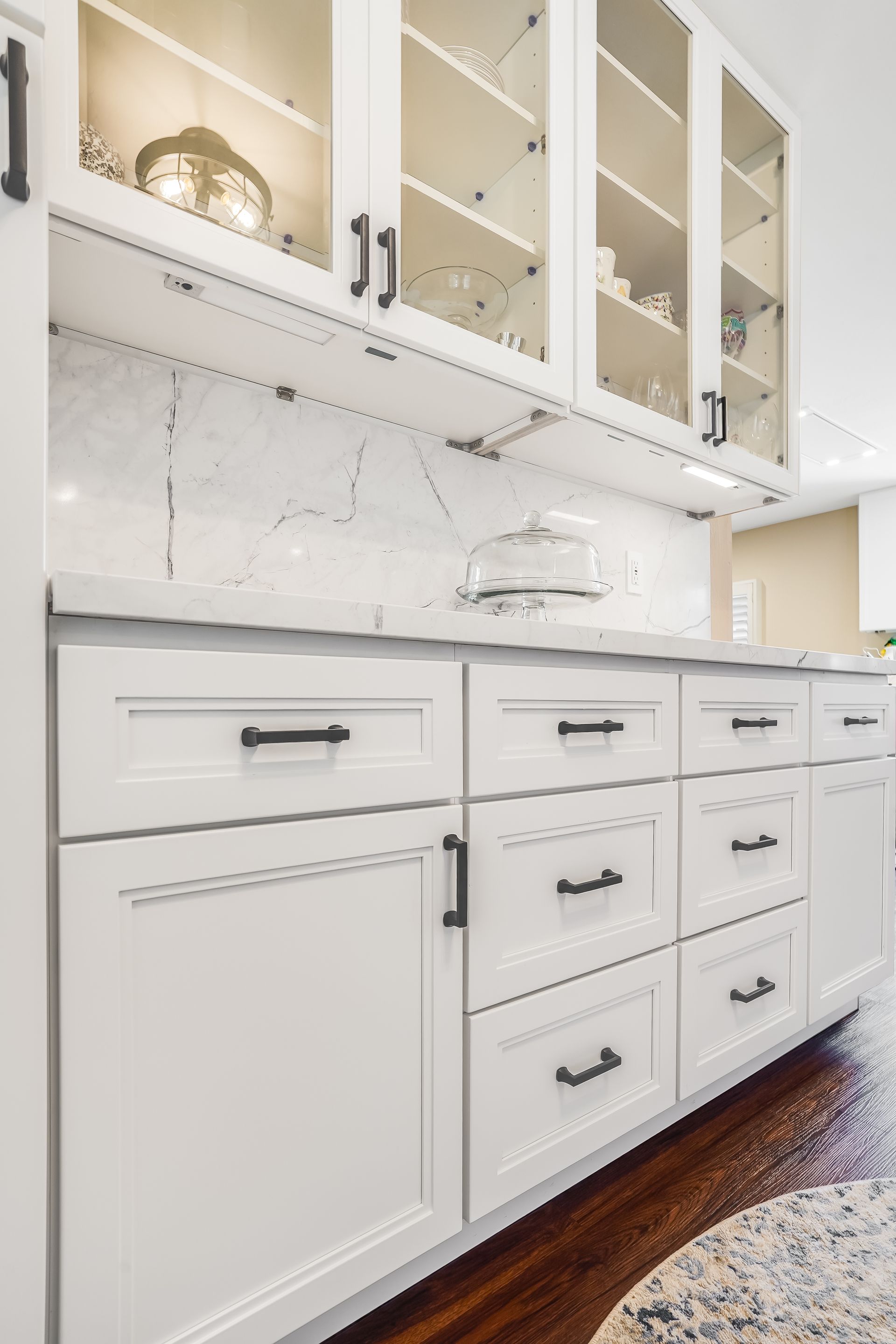White kitchen cabinets with black hardware and a marble backsplash.