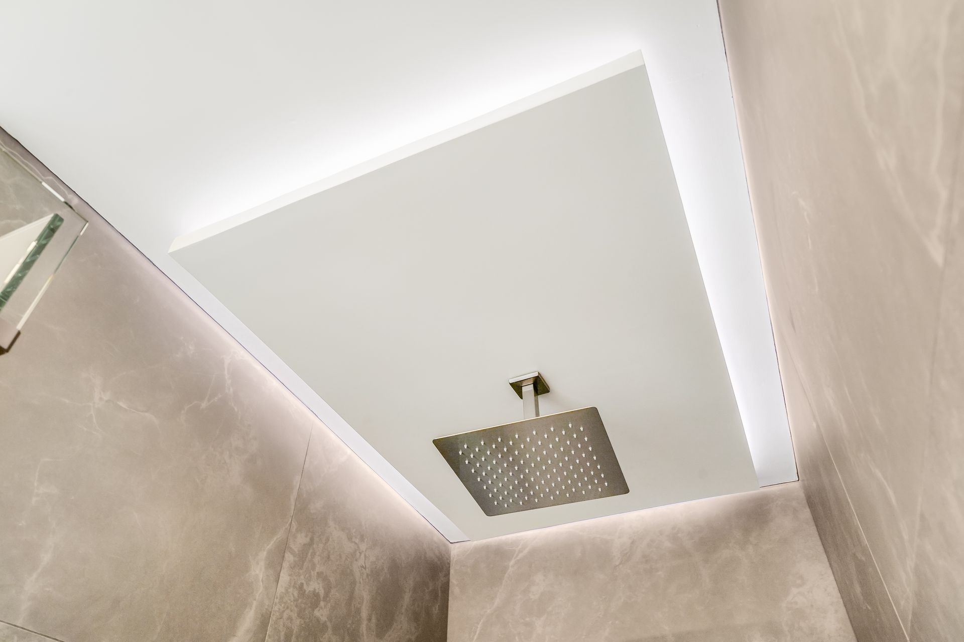 White ceiling with recessed lighting and a square rain showerhead. Gray tiled walls.