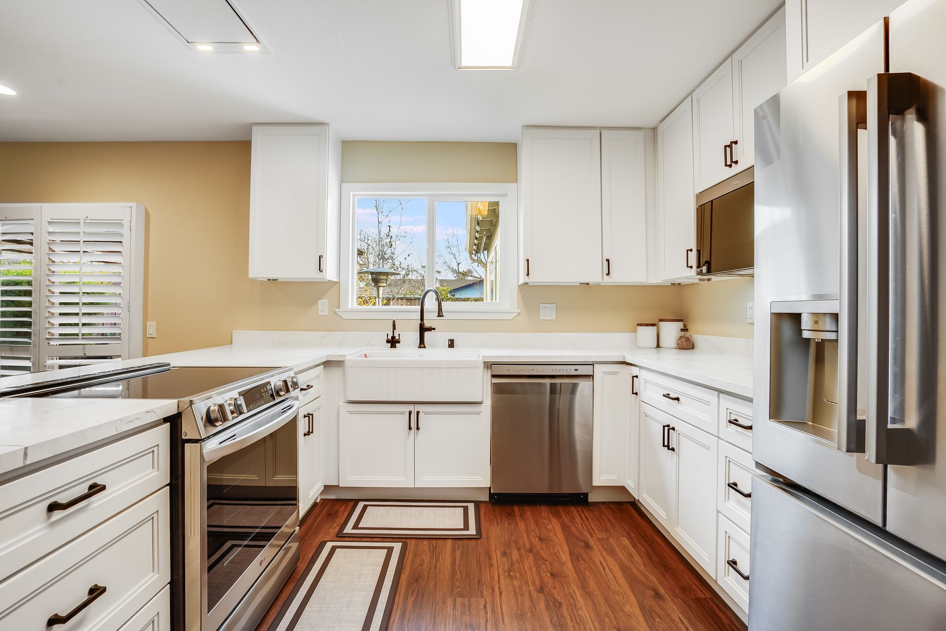 White kitchen with stainless steel appliances, white cabinets, and wood flooring.