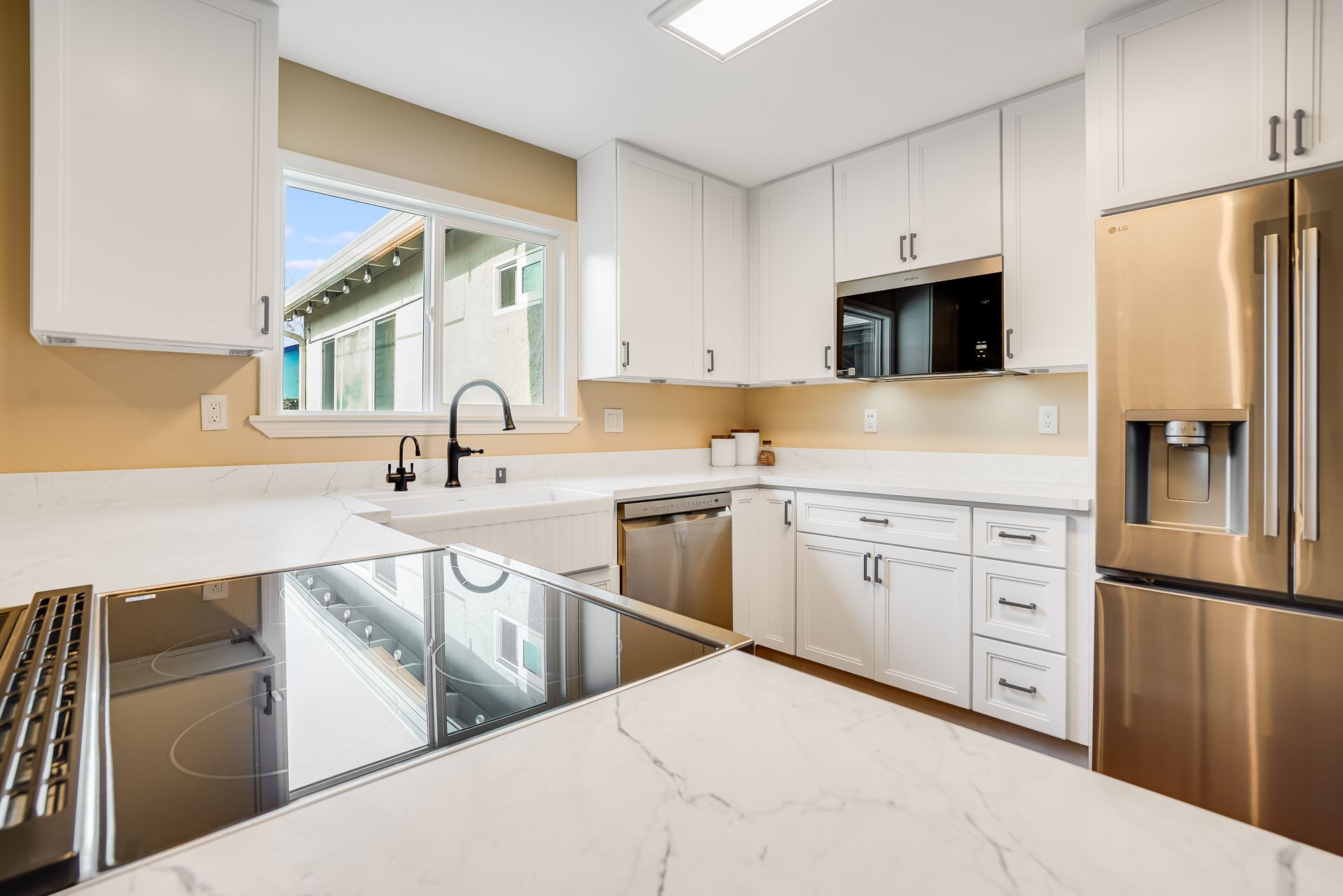 Modern kitchen with white cabinets, stainless steel appliances, and white countertops.