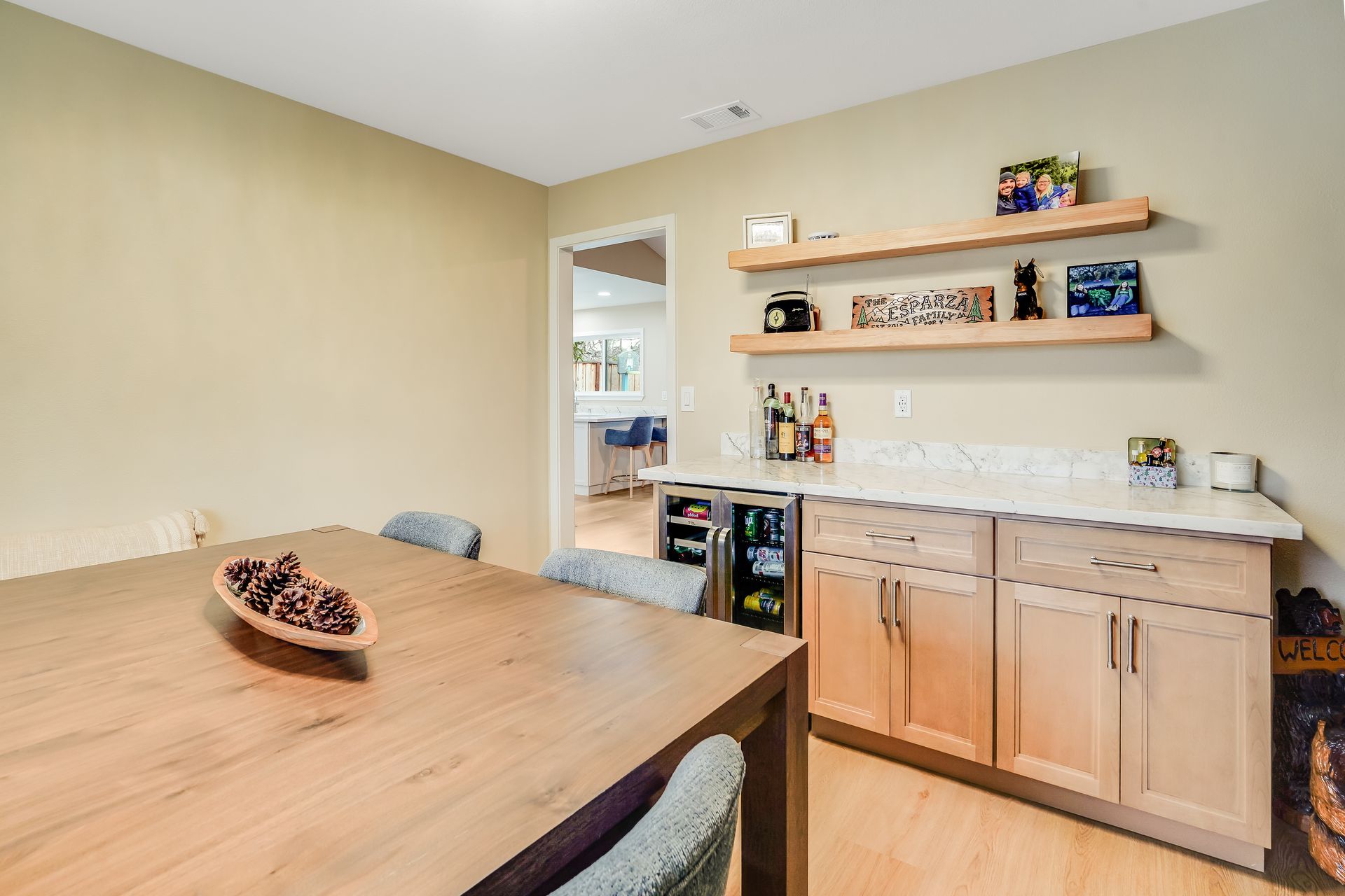 Dining room with wooden table, light cabinets, and floating shelves.