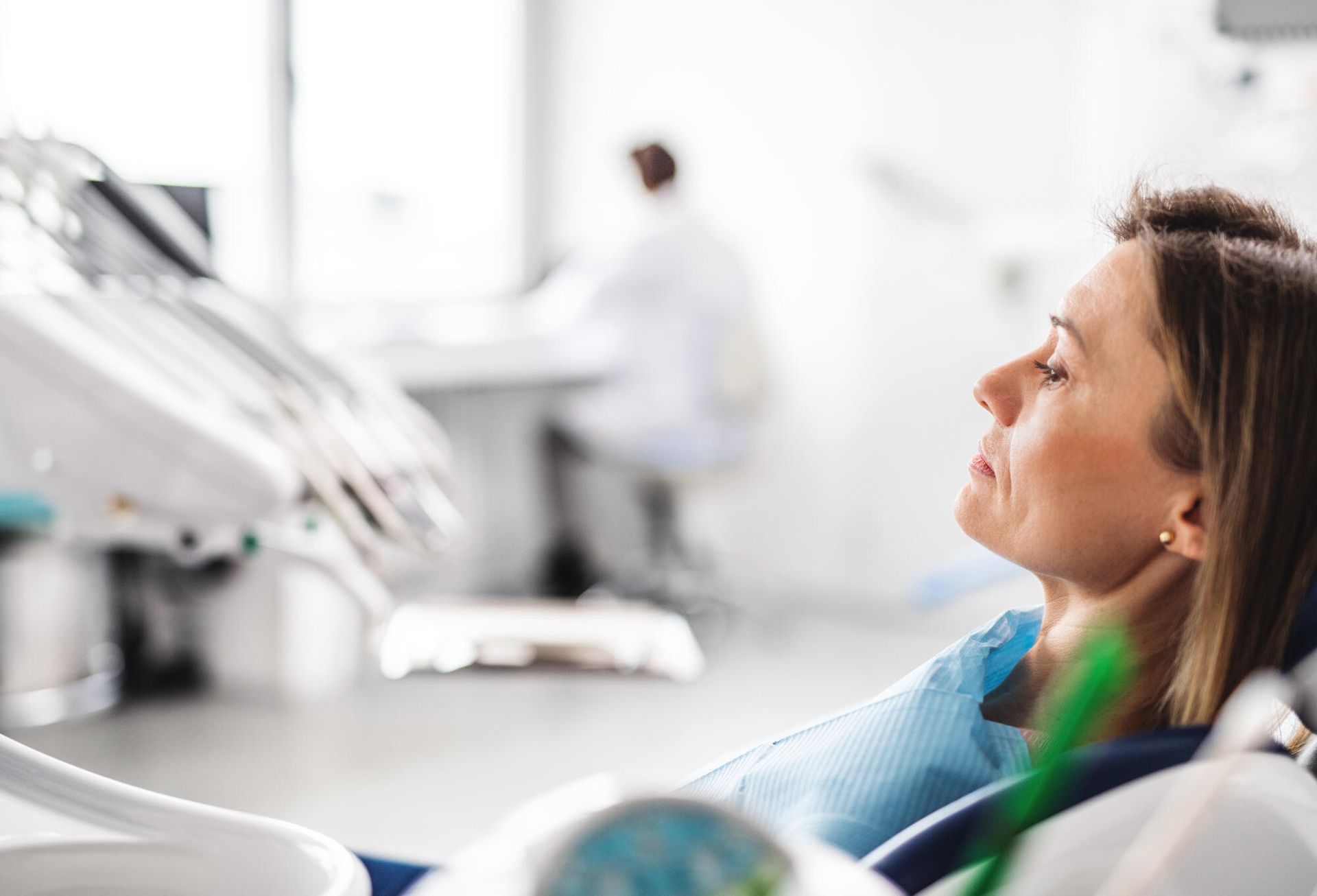 A woman is sitting in a dental chair with her eyes closed.