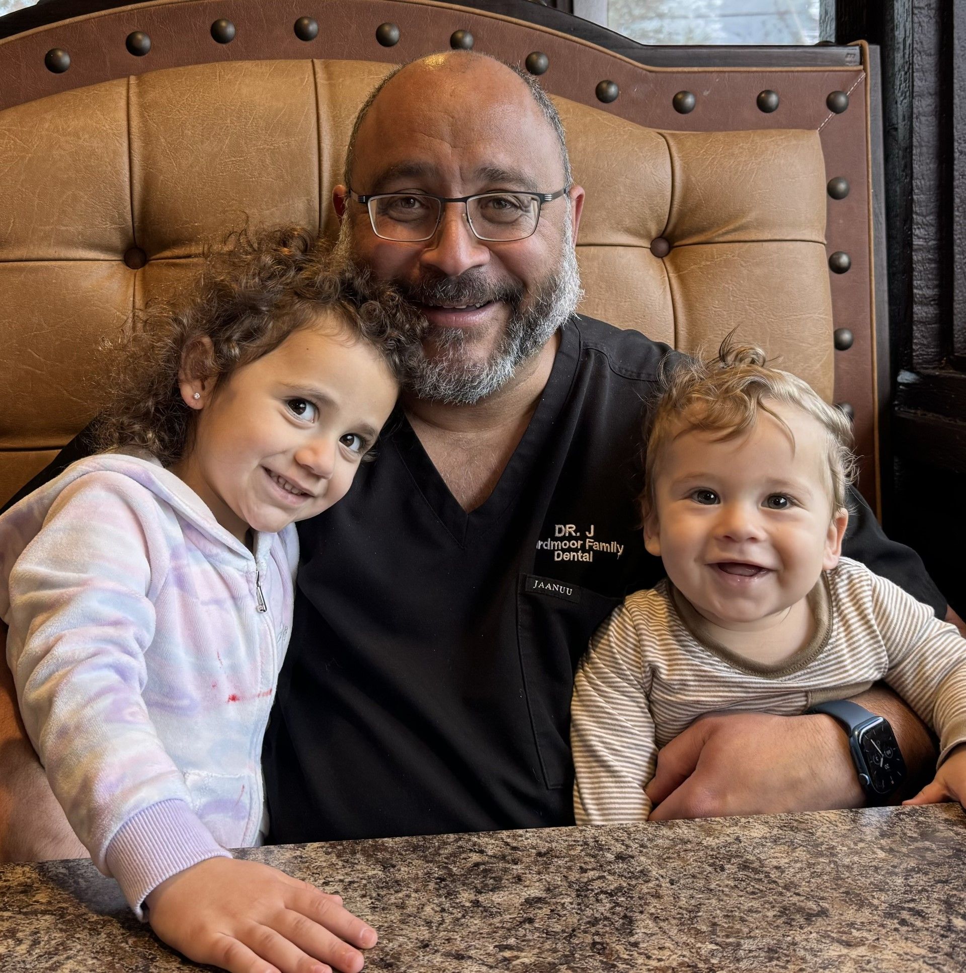 Dr. J and two children are posing for a picture and the man is wearing glasses