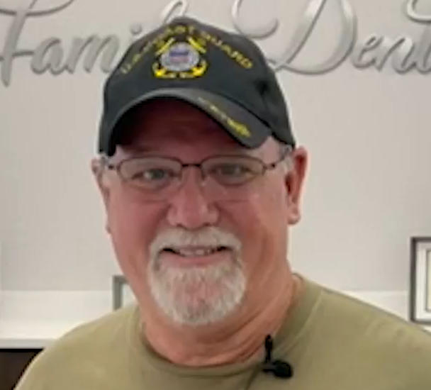 Man wearing Coast Guard hat and glasses, smiling.