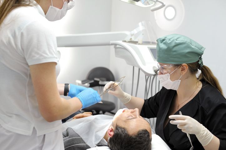 Dentist and assistant examining a patient in a dental office.