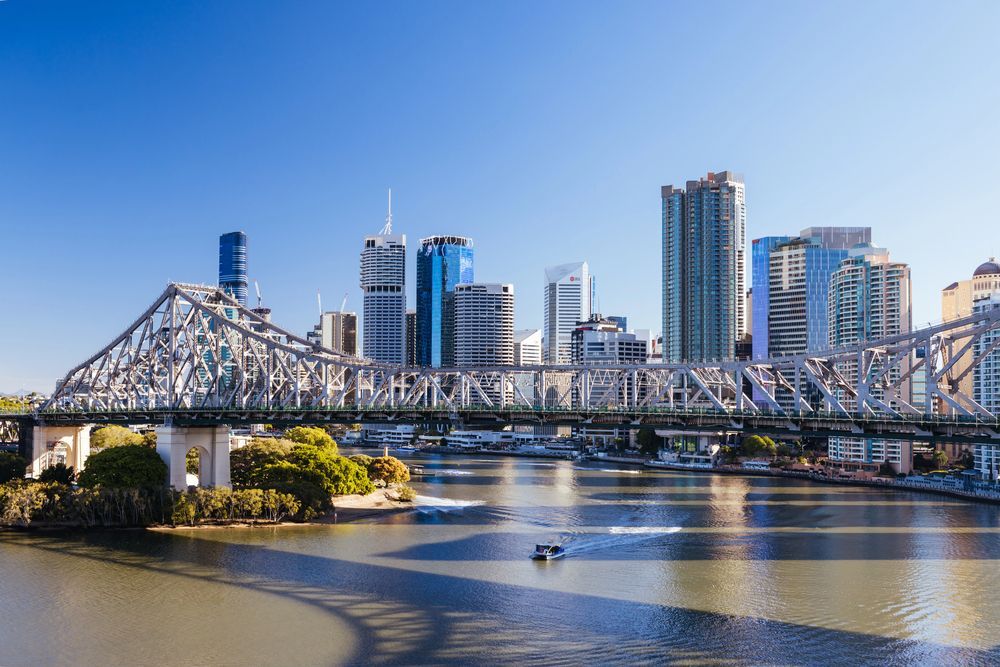 Brisbane city skyline with a steel bridge over a river on a clear day