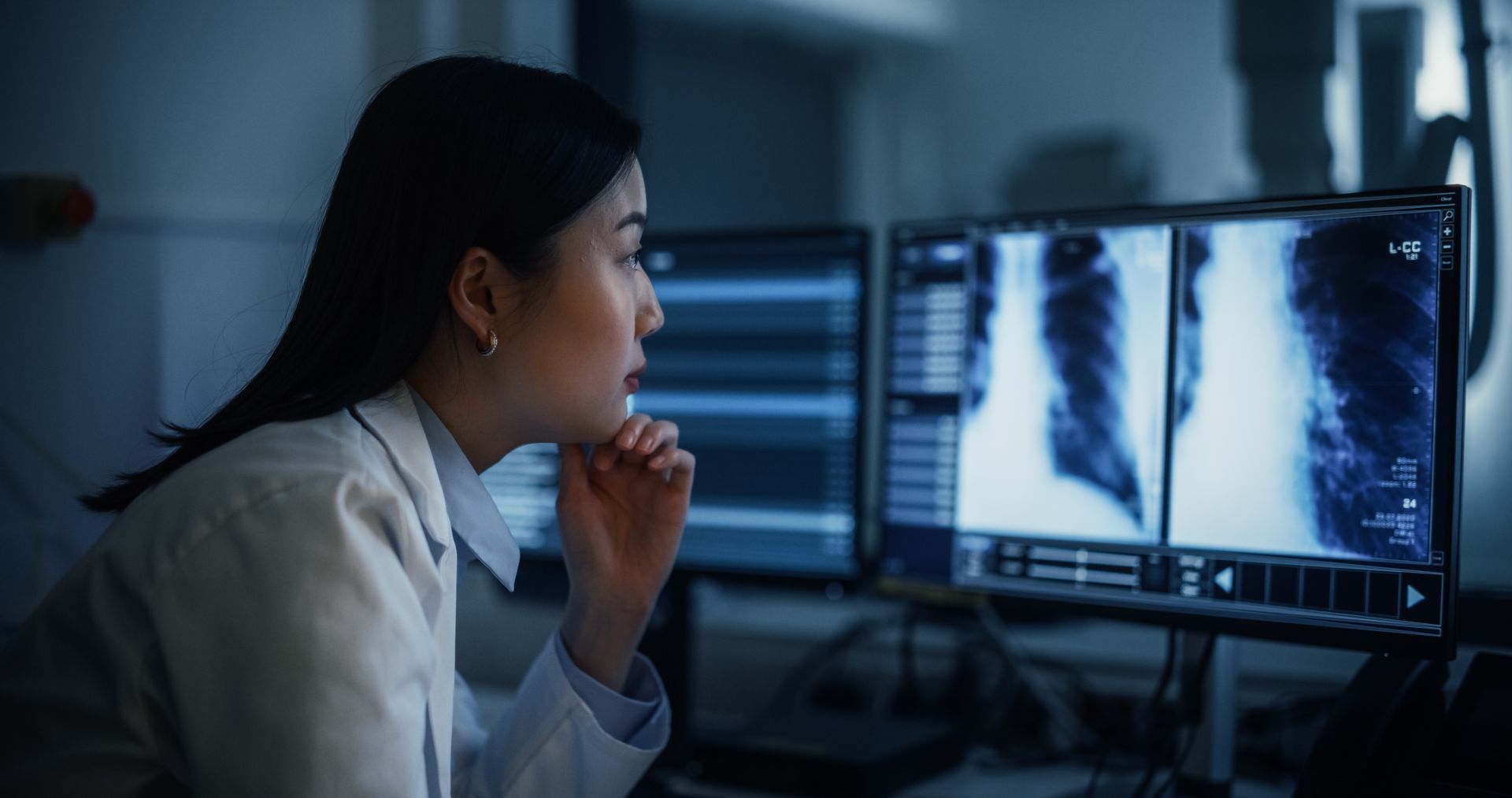 Doctor reviewing chest X-rays on a computer in a dim office