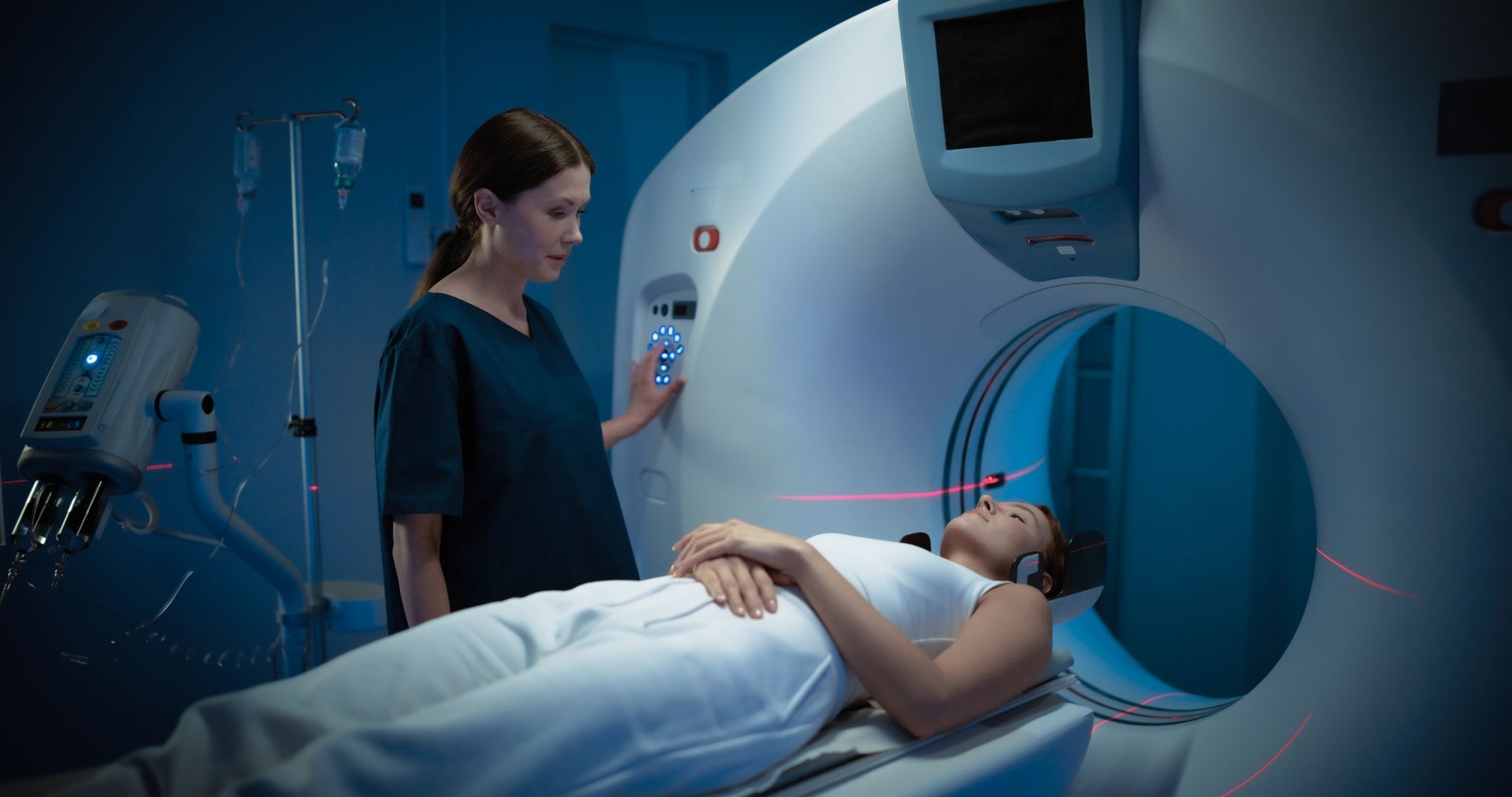 Woman in medical scanner, assisted by a healthcare worker in blue scrubs, medical setting.