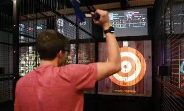 Person throwing an axe at a target in an indoor axe-throwing lane